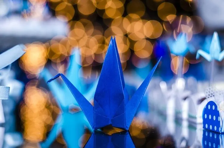 A blue origami crane among festive lights and decorations