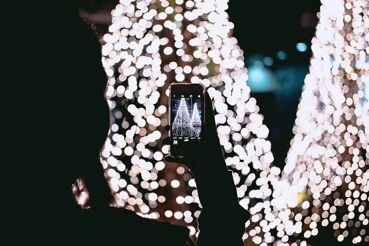 Someone photographing a display of string lights on a phone