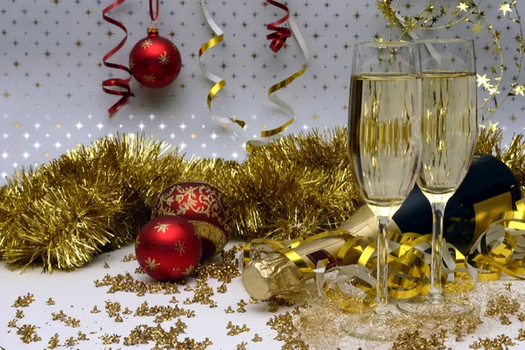 Champagne glasses, red baubles and gold tinsel on a table