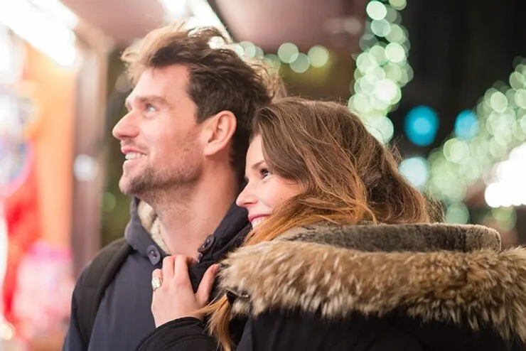 A couple looking up at holiday lights in a city street