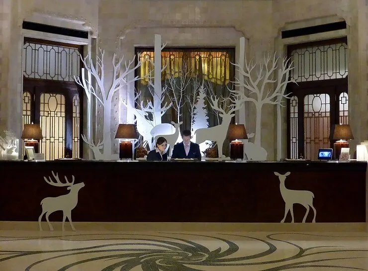 A hotel lobby decorated with white winter trees and reindeer silhouettes