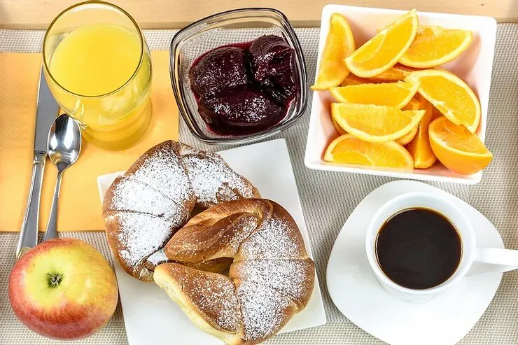 A hotel breakfast tray with juice, fruit, pastries and coffee