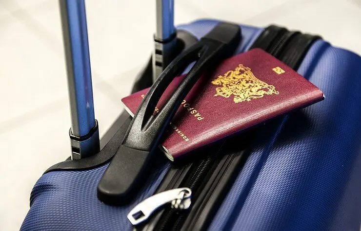 A passport and headphones on a blue suitcase