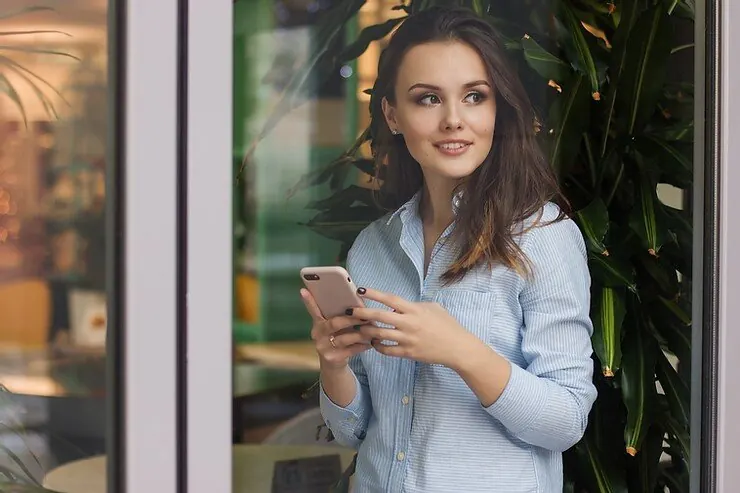 A woman holding a phone at a hotel entrance